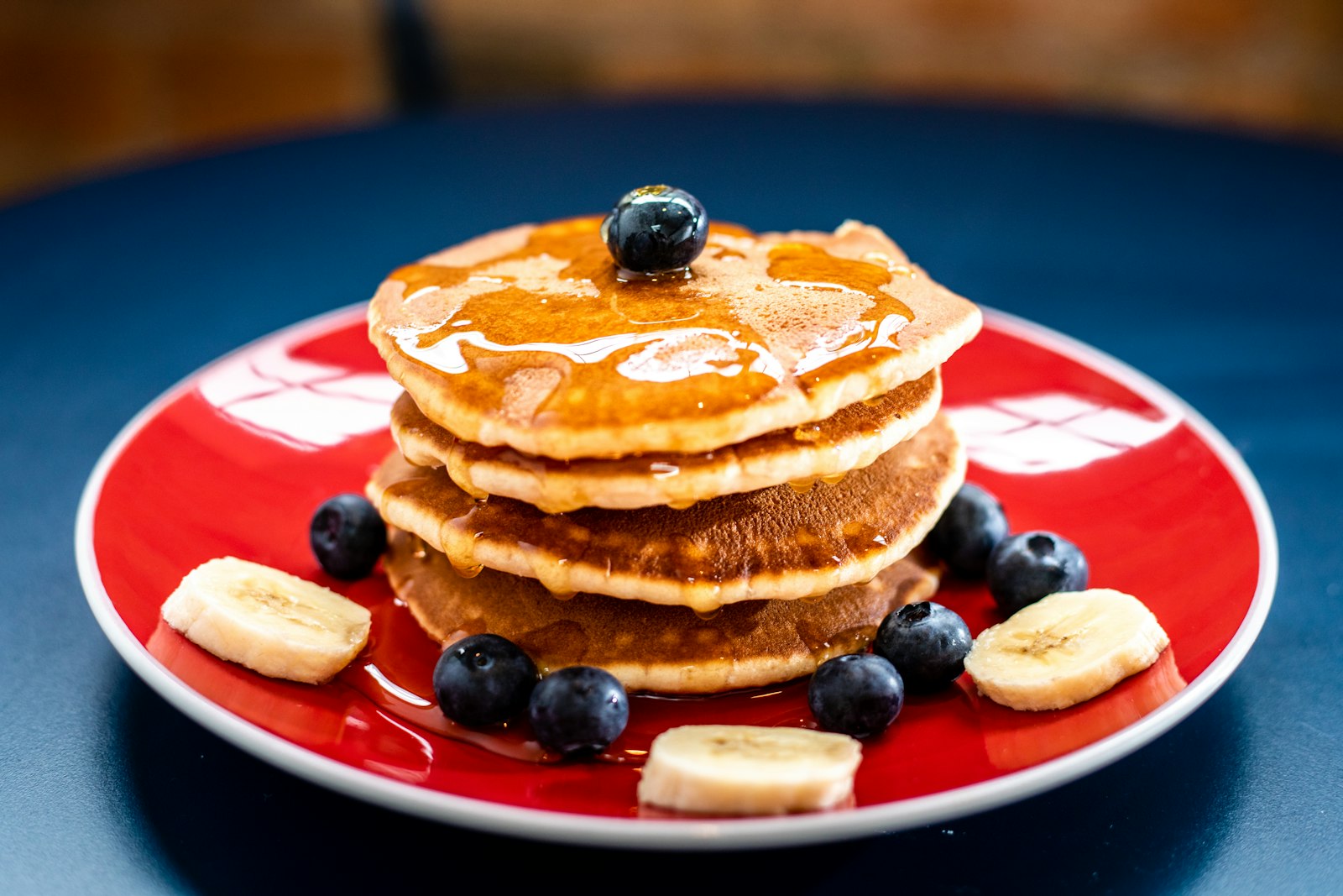 Pila di pancake con fettine di banana, mirtilli e sciroppo