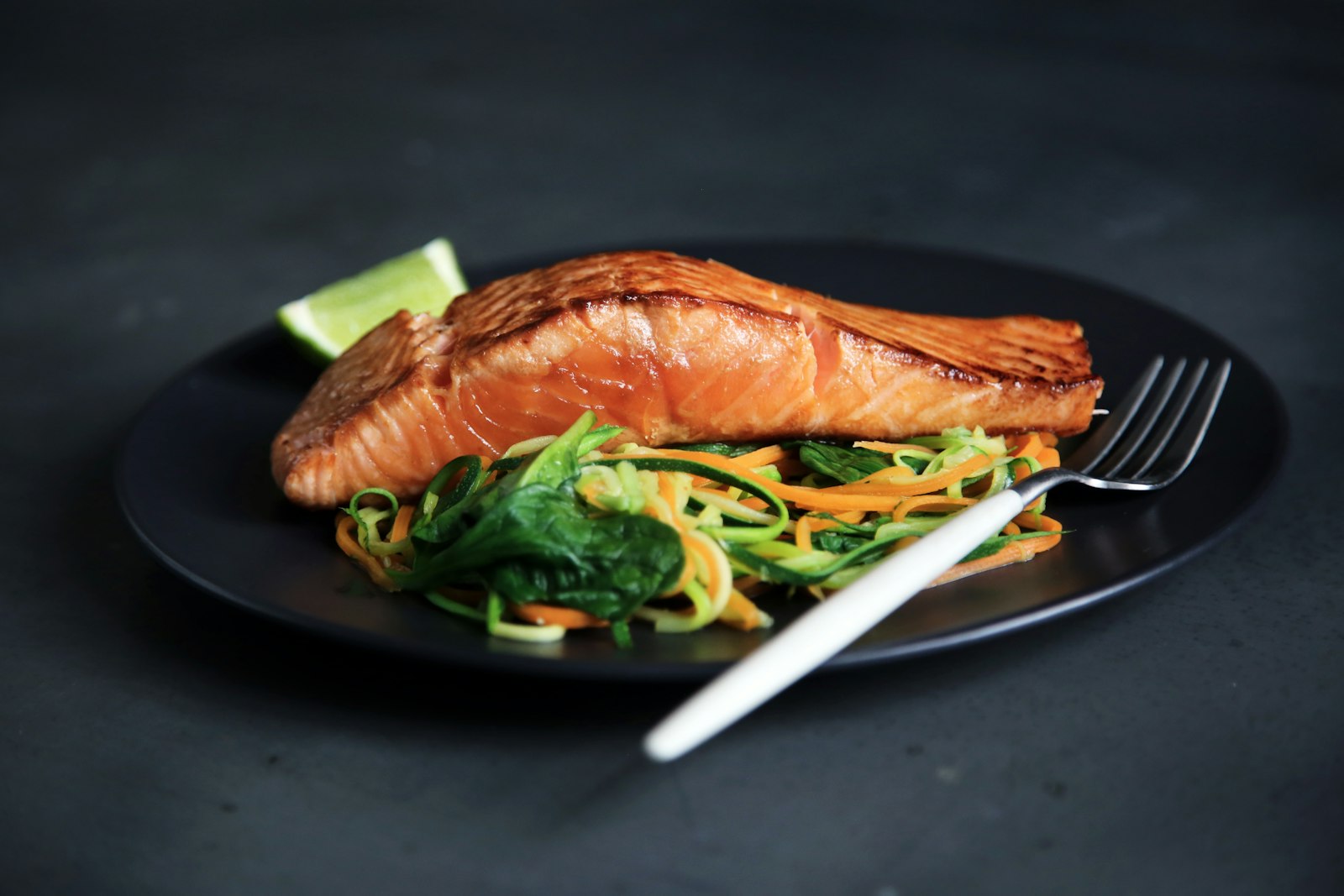 Filetto di salmone scottato con verdure su un piatto scuro